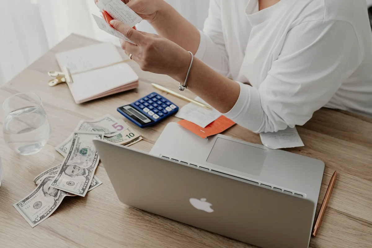 Registros financeiros conferidos ao lado de um computador